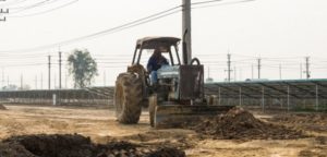 Petchaburi Thailand – February 20 2016: One worker drives wheel dozer in the under construction solar farm on February 20 2016 in Petchaburi Thailand