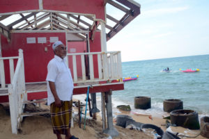 Haad Sai Resort's owner Domea Maha, 63, who built it just three years ago. He has lost two of the his 10 chalets to coastal erosion, including the one behind him, with the sand under its concrete foundation clawed away by the waves.