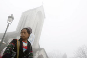A handicraft vendor waits for customers on a foggy day in front of a Catholic church after Sunday Mass in Vietnam's northwestern resort town of Sapa on Feb 21, 2016. 