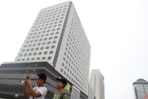 Young men men take photos in front of high-rise buildings in central Yangon, Myanmar on July 25, 2016.